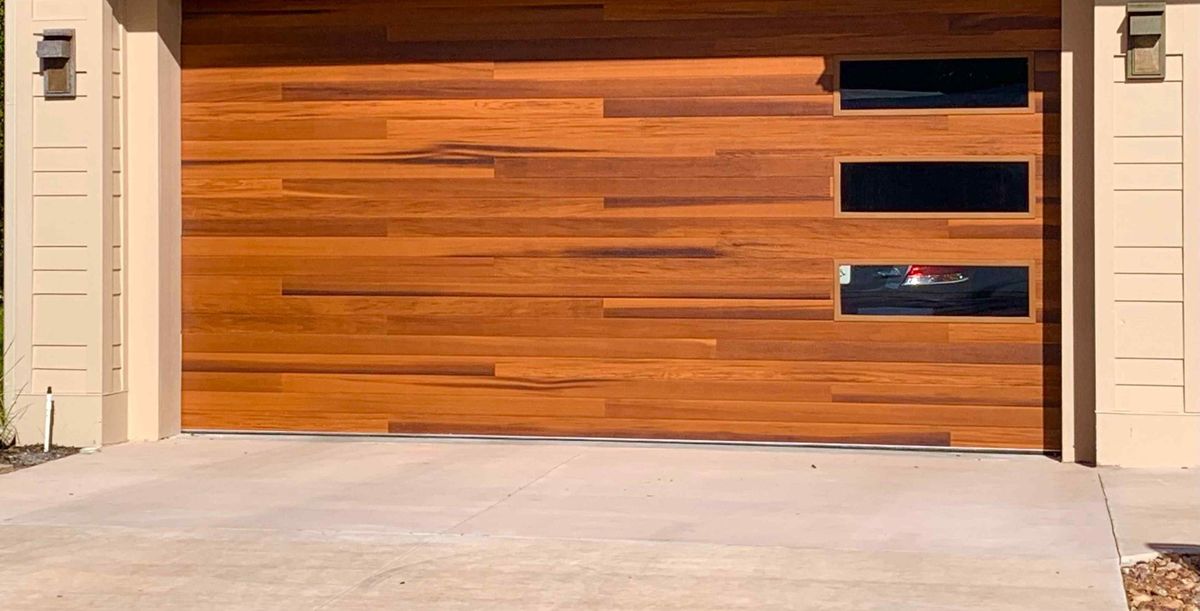 A wood-look replacement garage door with dark window panels
