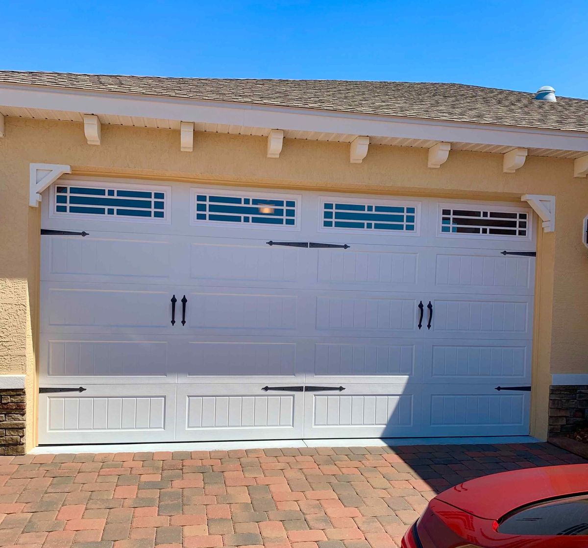 A white carriage-style garage door above a paver driveway