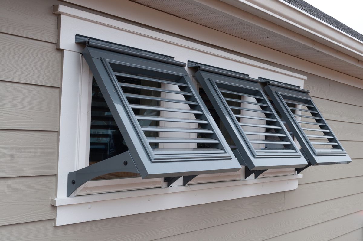 Louvered metal storm shutters on a siding wall