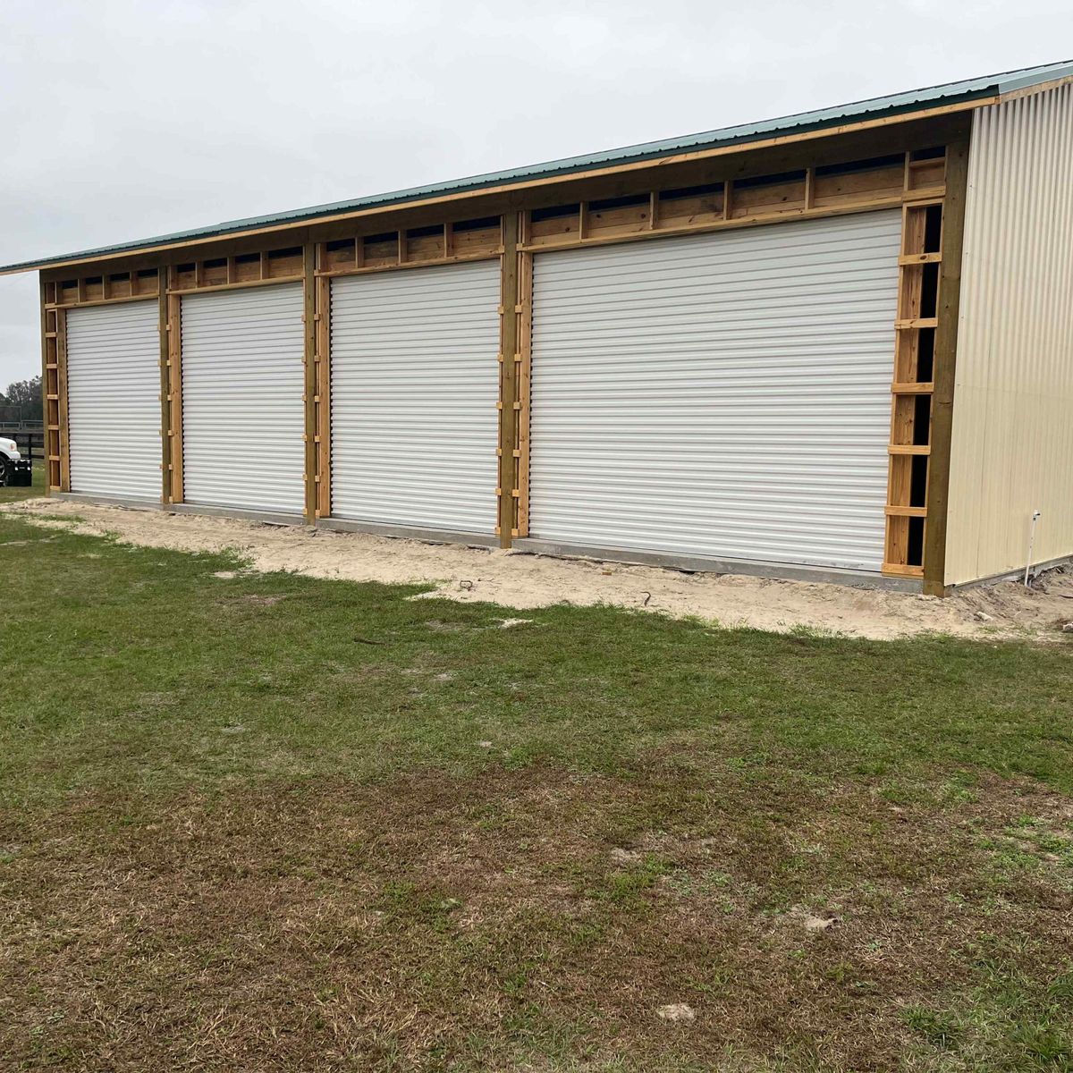 A metal building with three new white roll-up garage doors