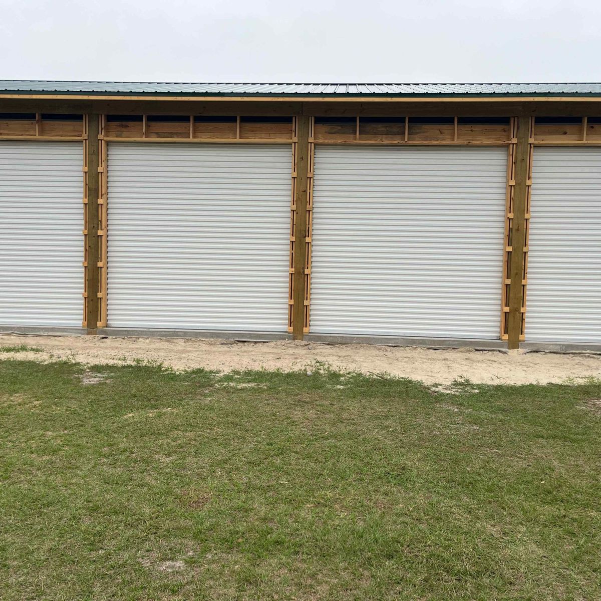 A metal outbuilding with four new white roll-up doors