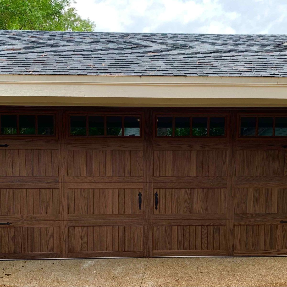 A new wood-look garage door with window panels on a tan Central Florida home