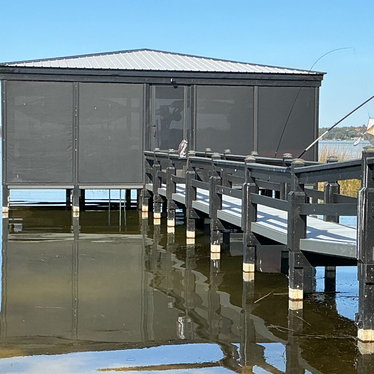 A dock house on the lake enclosed in dark motorized screens